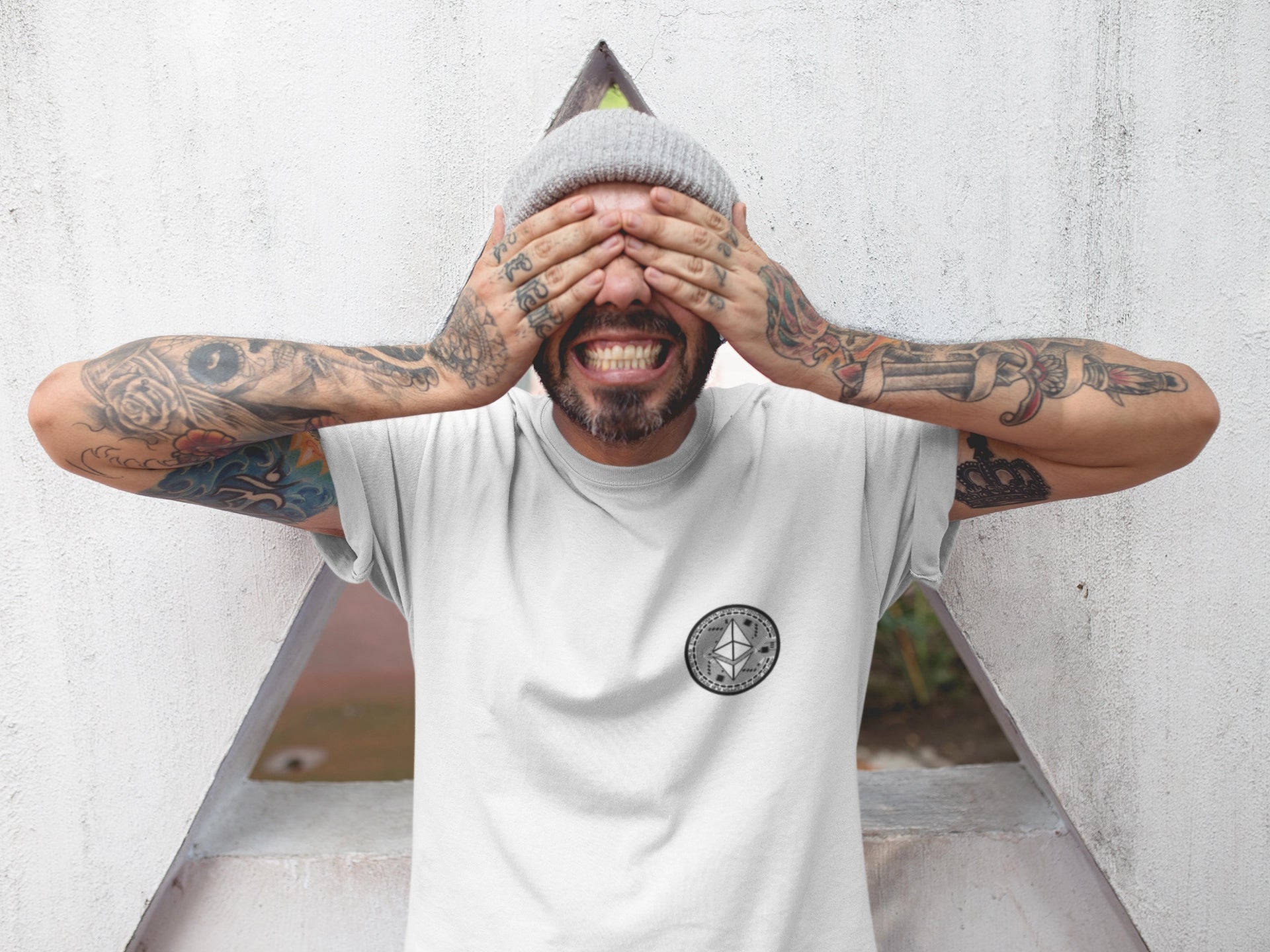 Tattooed Man covering his eyes while wearing CRYPWEAR CRYPTO Collection White Ethereum Shirt